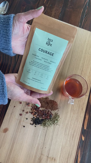 Hands showing organic herbal tea in package, loose leaf tea and a cup with the tea. 